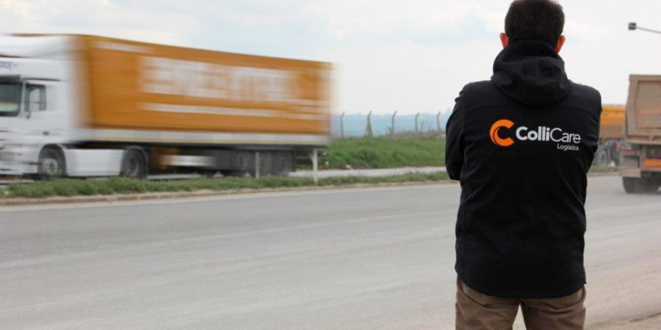 ColliCare employee on the side of the freeway watching the trailers passing by filled with goods