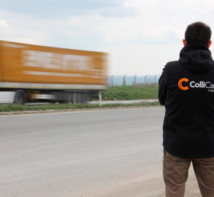 ColliCare employee on the side of the freeway watching the trailers passing by filled with goods